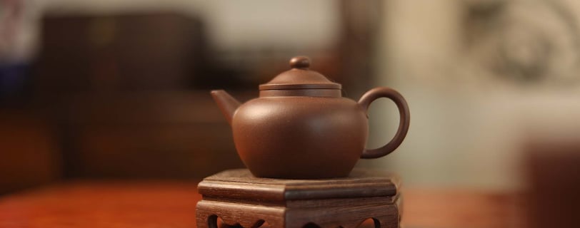 Brown teapot placed on a wooden stand