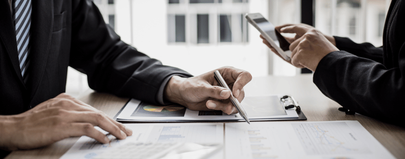 Pessoas analisando gráficos e dados financeiros em reunião, representando organização e planejamento