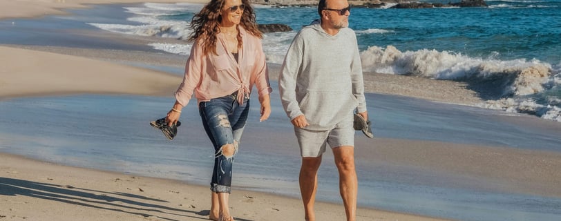 Pareja de jubildados caminando por la Playa al migrar a España