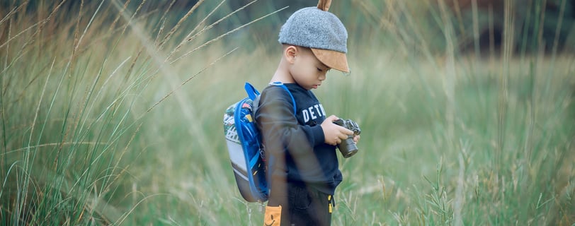 a young boy in a hat and a backpacker