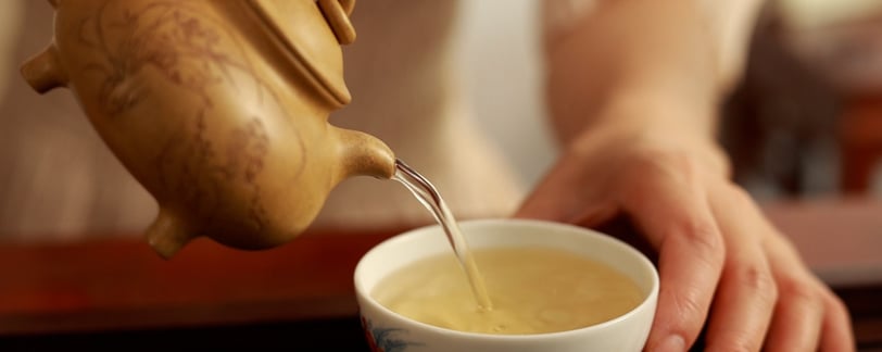 pouring tea from a teapot into a teacup