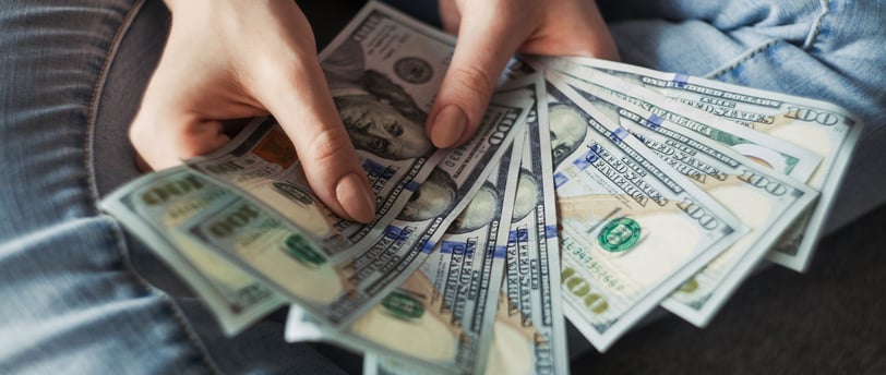 person holding a wad of 100 dollar bills in their hand