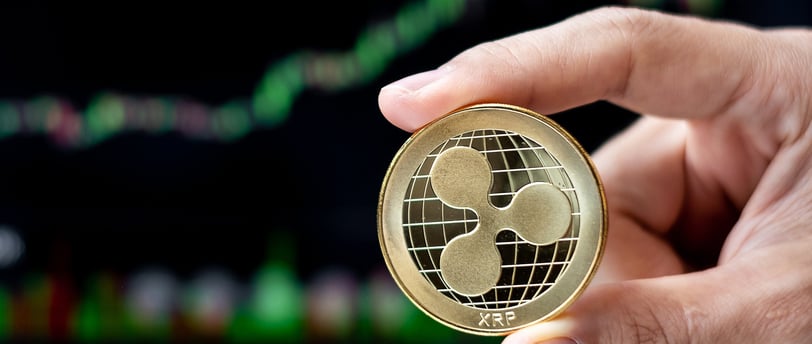 ripple xrp token in someones hands with charts in background