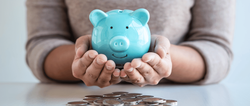 woman holding a piggy bank with coins on the table for retirement