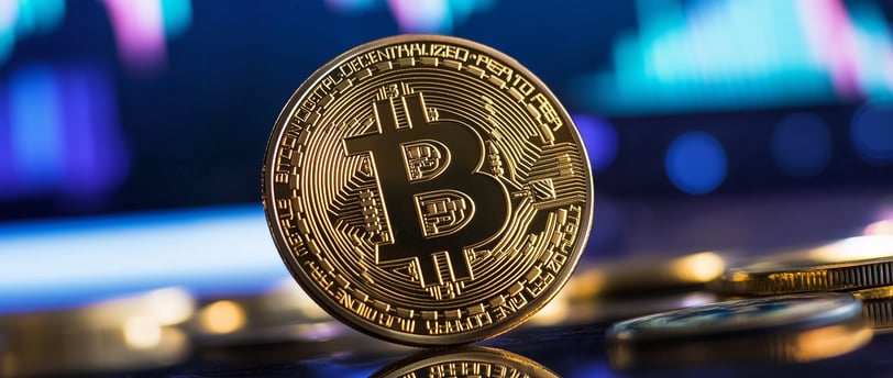 bitcoin on black surface with charts in background