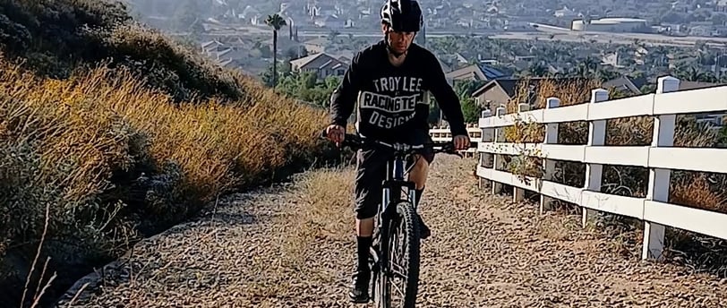 Mountain biker climbing a loose gravel trail, staying seated for traction and control