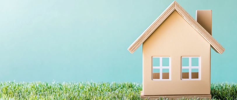 mini house on grass for symbolizing real estate ira investing
