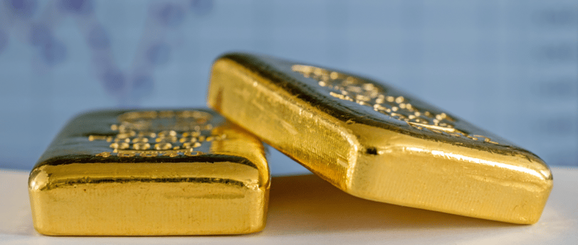 gold bullion bars on a flat surface with chart in the background