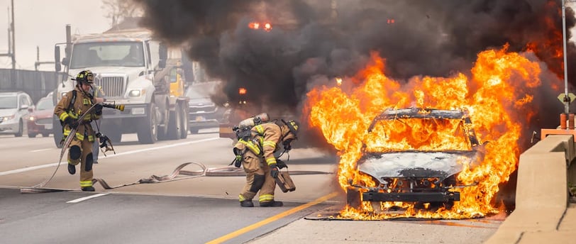 a firefighter standing in front of a car that is on fire
