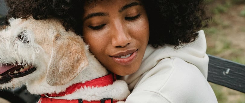 woman hugging dog on park bench