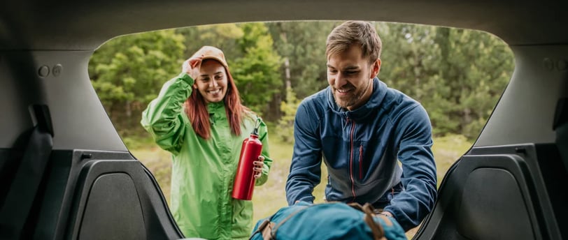 Couple packing their bags in the trunk of their car ready to go hiking for the day