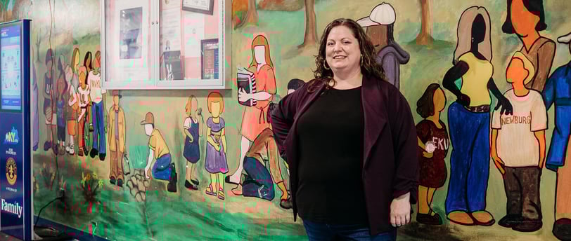 Woman in purple sweater standing in front of painted mural