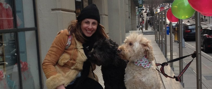mulher com casaco de frio ao lado de dois cães, um preto e outro branco