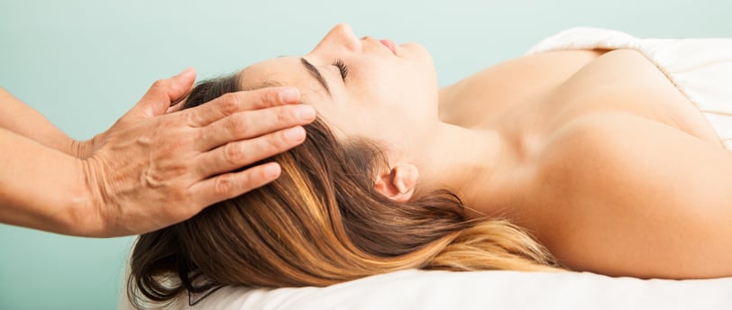 uma terapeuta impondo as mãos sobre a cabeça de uma mulher para a terapia reiki