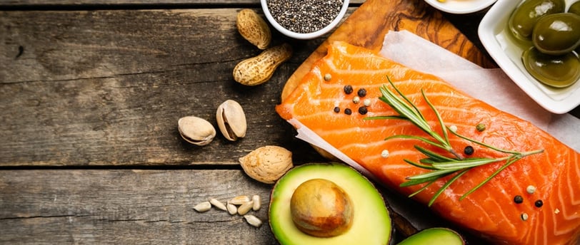 A wooden table featuring salmon, avocado, highlighting nutrient-dense foods for metabolic.