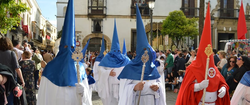 People in Blue and Red Robes Walking on the Street of Seville on Semana Santa