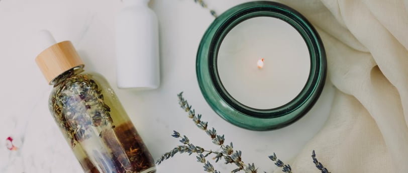 Candle, lavender, and herbal oil flatlay