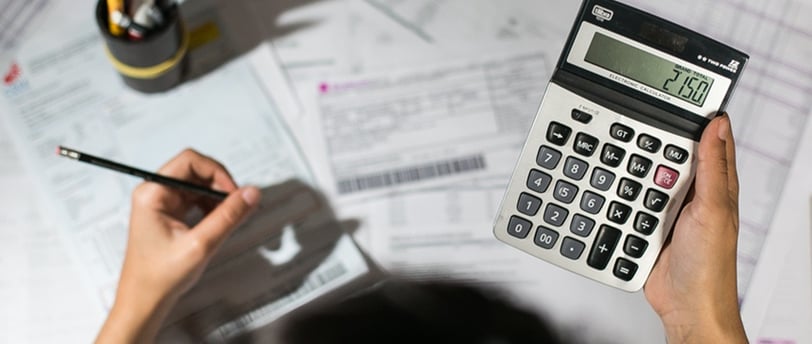 a person holding a calculator and a pen