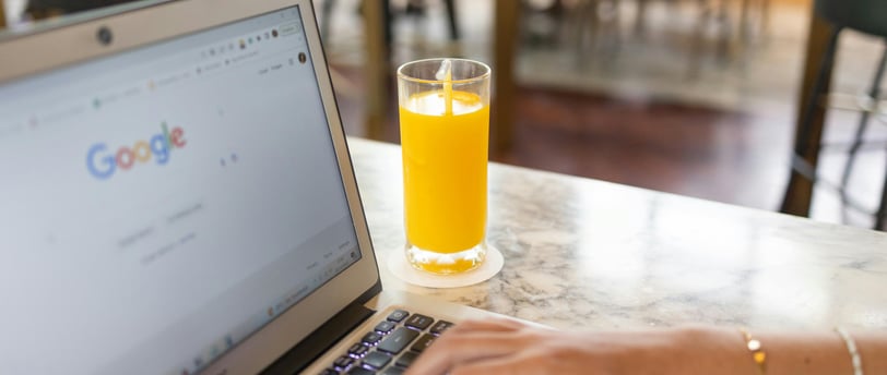 a person using a laptop computer and a glass of orange juice