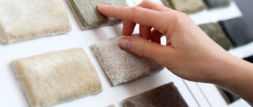 a person's hand holding a piece of carpet with a finger on it