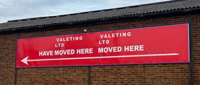 Big red sign on brick wall that reads Valeting Ltd have moved here Valeting Ltd moved here