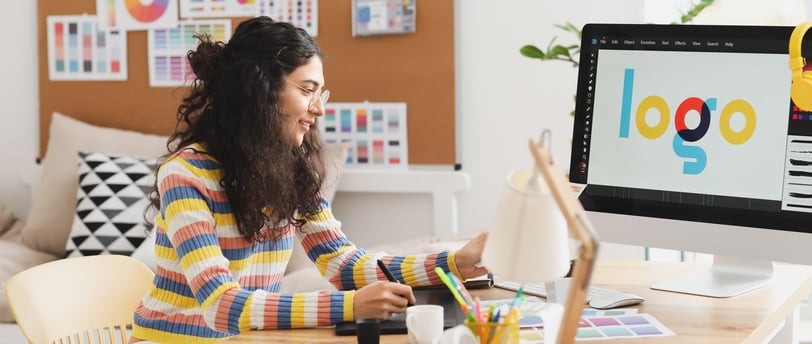 a woman sitting at a desk with a computer monitor and a laptop