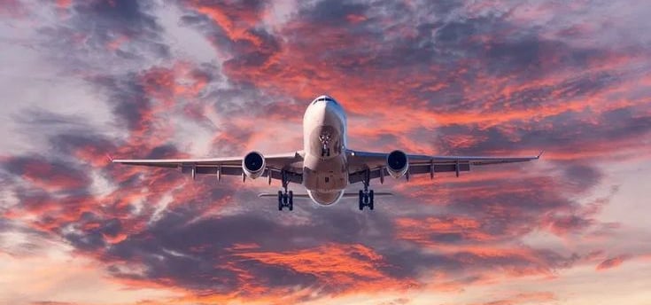 a plane taking off into the sunset