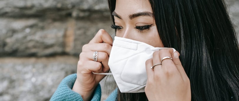 a woman in a blue sweater and a white mask