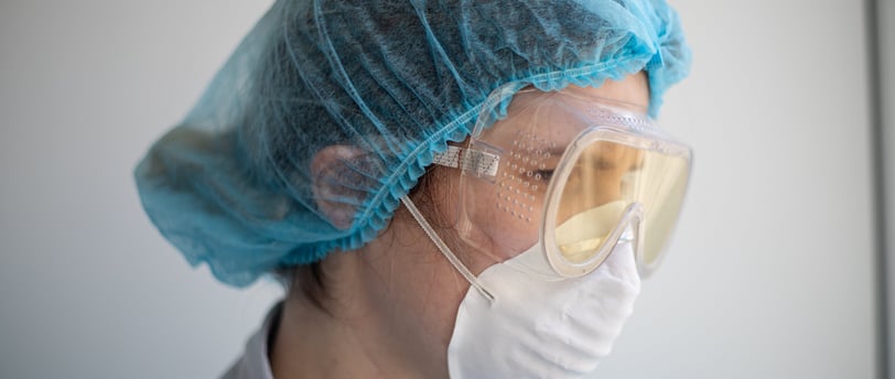 a woman in a blue scrub suit and goggles