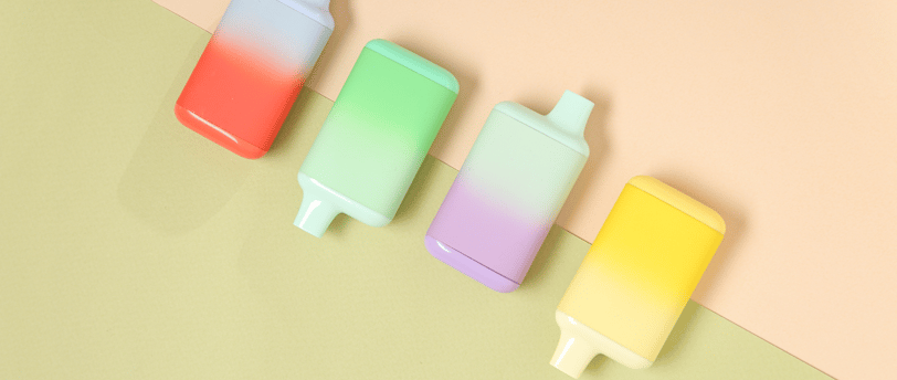 Colorful pastel disposable vapes laid out on a soft color-blocked background.