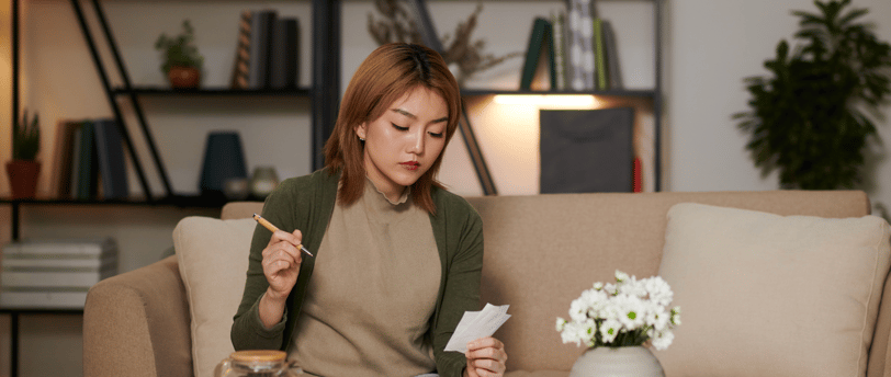 Woman calculating IVF costs at home with documents and calculator