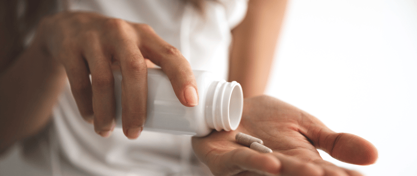Woman taking fertility supplements from a bottle