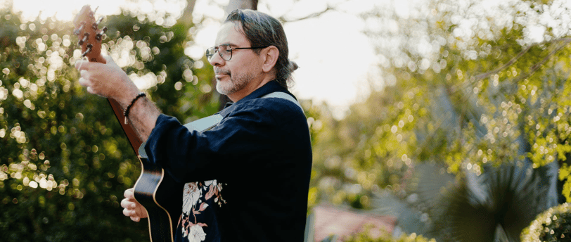 a man playing guitar in a backyard