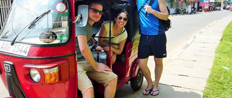 three people standing around a red tuk tuk tuk