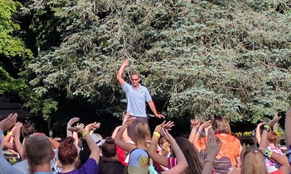 Johnny teaching children Tai Chi outdoors on a picnic table at Make Arthritis Stop Hurting Camp