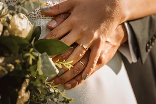 a bride and groom holding hands in front of a bouquet