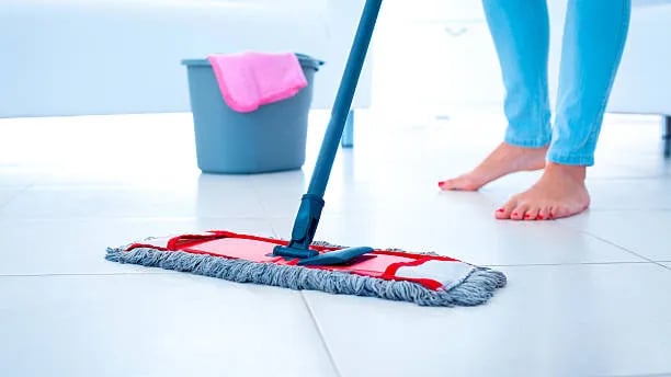 a woman cleaning a tile floor with a mop