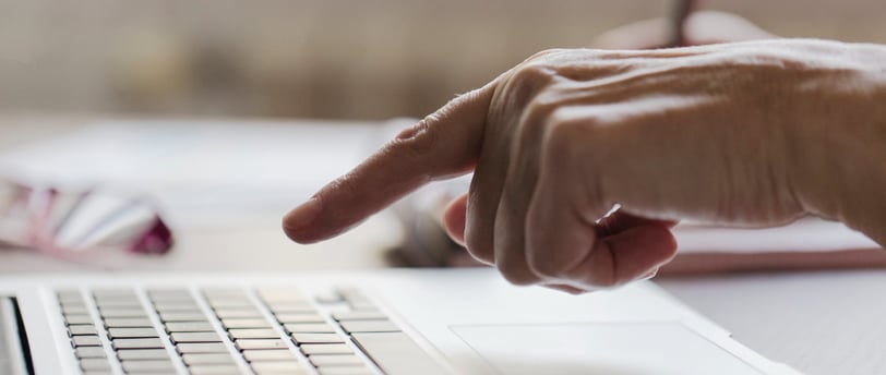 Mão apontando para o teclado de notebook