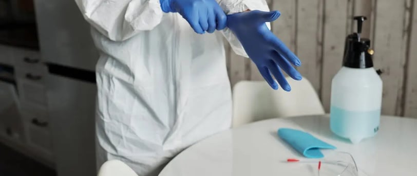 a person in a white lab coat and gloves and sanitizing tools