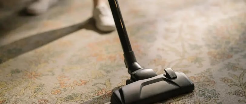 a person using a vacuumr to clean a carpet