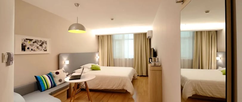 a clean bedroom with a couch and a bed in the background