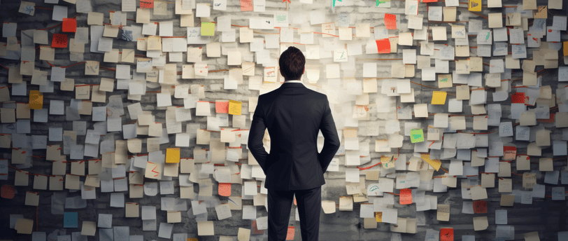 A man in a suit, facing a wall of to-do lists and overwhelmed by the burdens on his time