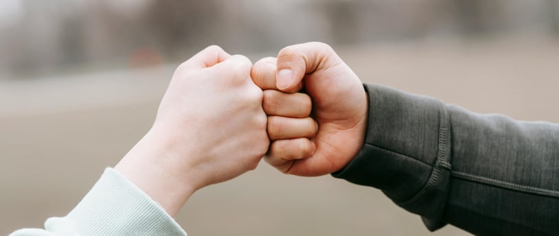 two trusting friends fist-bumping