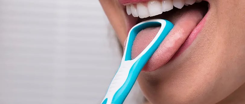 a girl using tongue cleaner in mouth