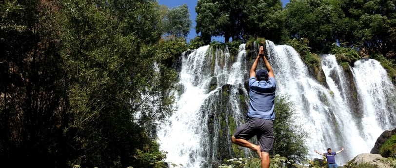 a man standing on a rock in front of a waterfall
