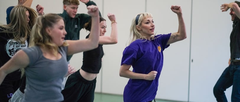 A group of dancers holding their arms up mid dance