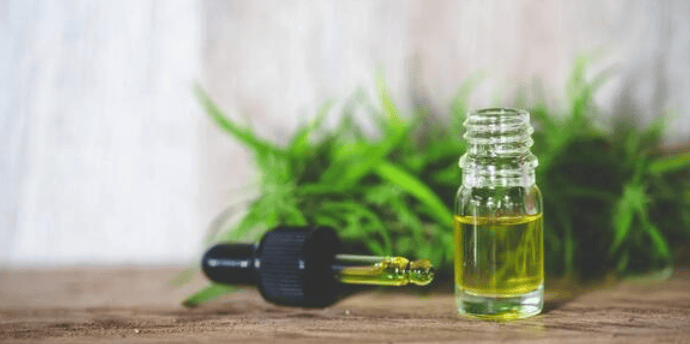 a bottle of oil with a plant in the background