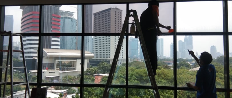 a man is standing on a ladder to get a picture of a window