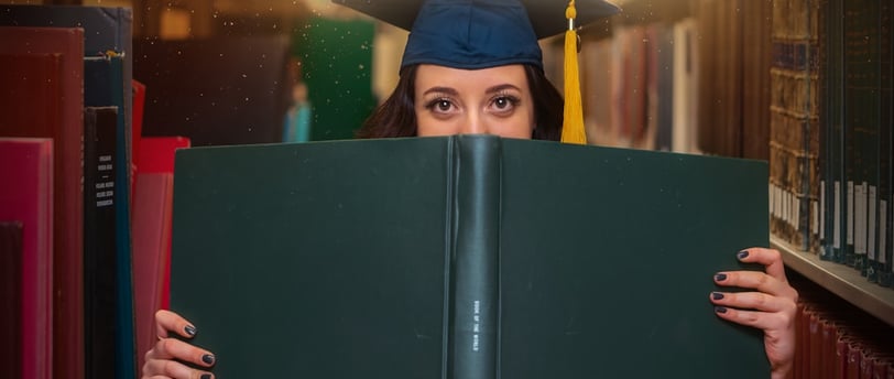 graduate peering over book