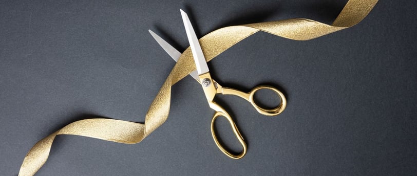 a pair of scissors cutting a gold ribbon